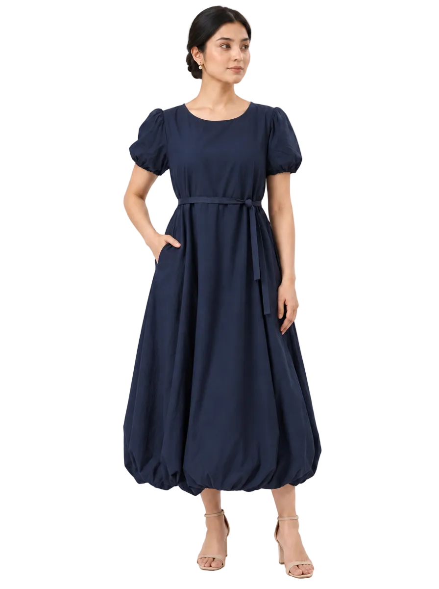 Front three-quarter view of The Lamorah navy balloon-hem dress with puff sleeves, side pocket and separate narrow sash.