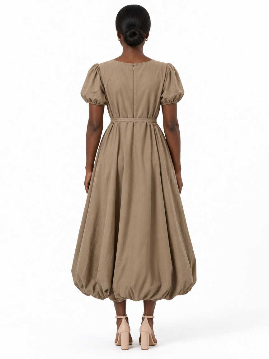 Back view of The Lamorah taupe balloon-hem dress showing the centre-back zipper, puff sleeves, narrow waist sash and rounded hem.
