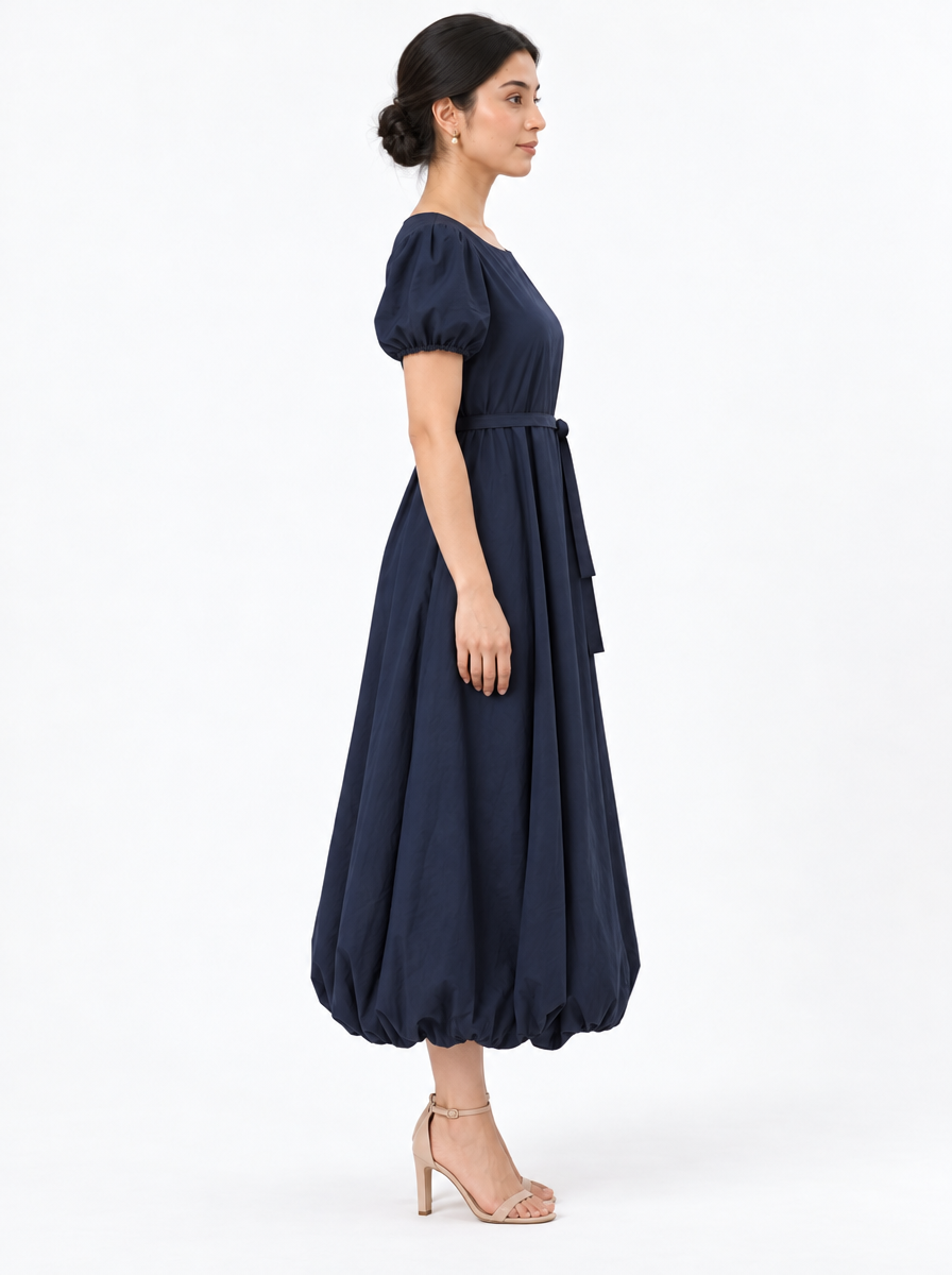 Side profile of The Lamorah navy puff-sleeve dress showing the rounded balloon hem and separate waist sash.