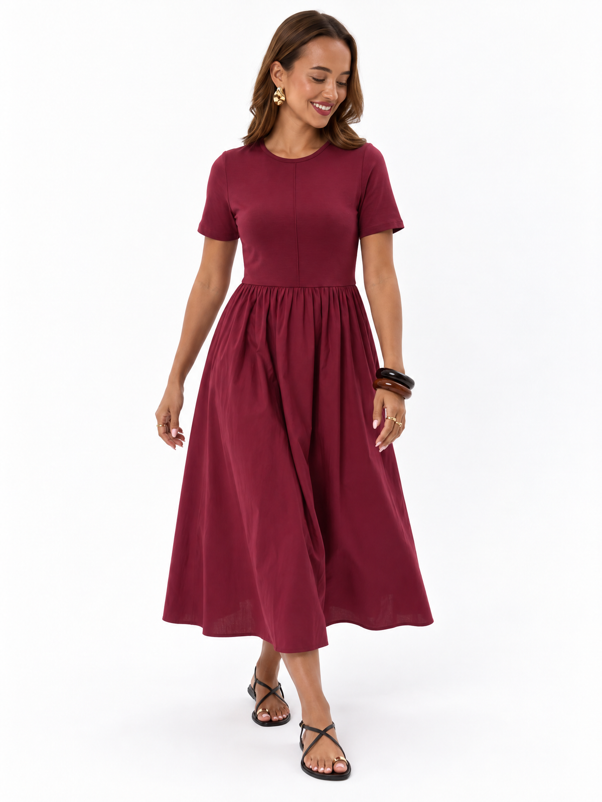 Model walking in THE LAMORAH burgundy stretch-bodice midi dress, showing the movement of the full gathered skirt, styled with flat sandals.