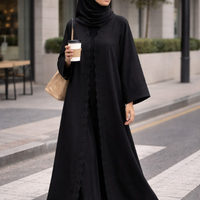 Woman in a black abaya holding a coffee cup on a city street. |THE LAMORAH
