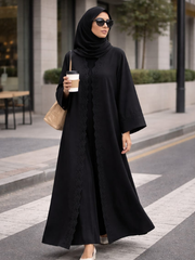 Woman in a black abaya holding a coffee cup on a city street. |THE LAMORAH
