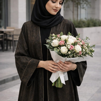 Woman in a black hijab holding a bouquet of flowers outdoors. |THE LAMORAH
