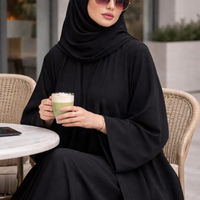 Woman in black abaya holding a drink outdoors |THE LAMORAH
