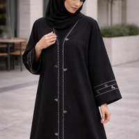 Woman wearing a black abaya with intricate designs outdoors. |THE LAMORAH
