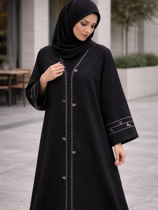 Woman wearing a black abaya with intricate designs outdoors. |THE LAMORAH
