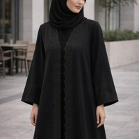Woman wearing a black abaya with lace details outdoors. |THE LAMORAH
