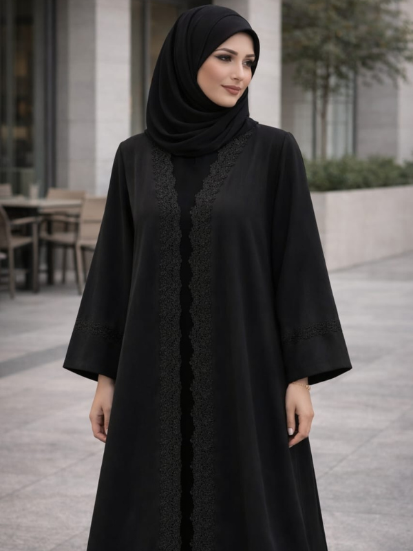 Woman wearing a black abaya with lace details outdoors. |THE LAMORAH
