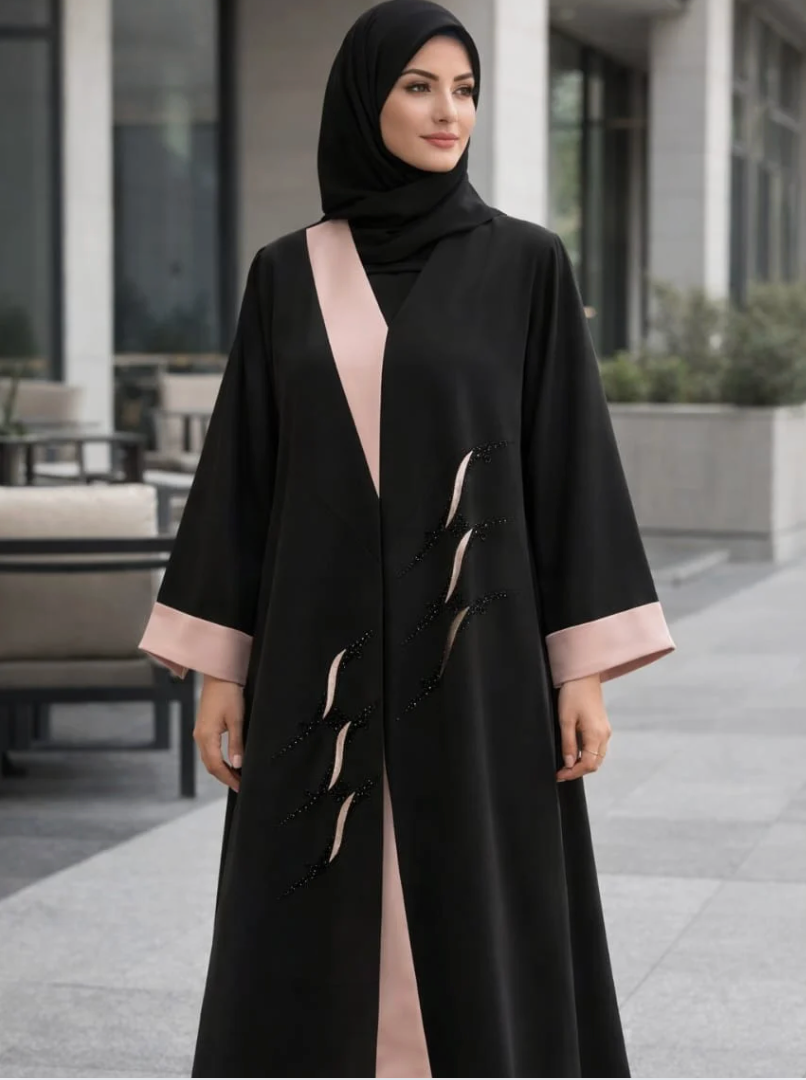 Woman wearing a black abaya with pink accents standing outdoors |THE LAMORAH
