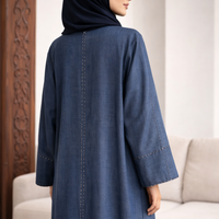 Woman wearing a blue abaya with a hijab in a living room setting | THE LAMORAH