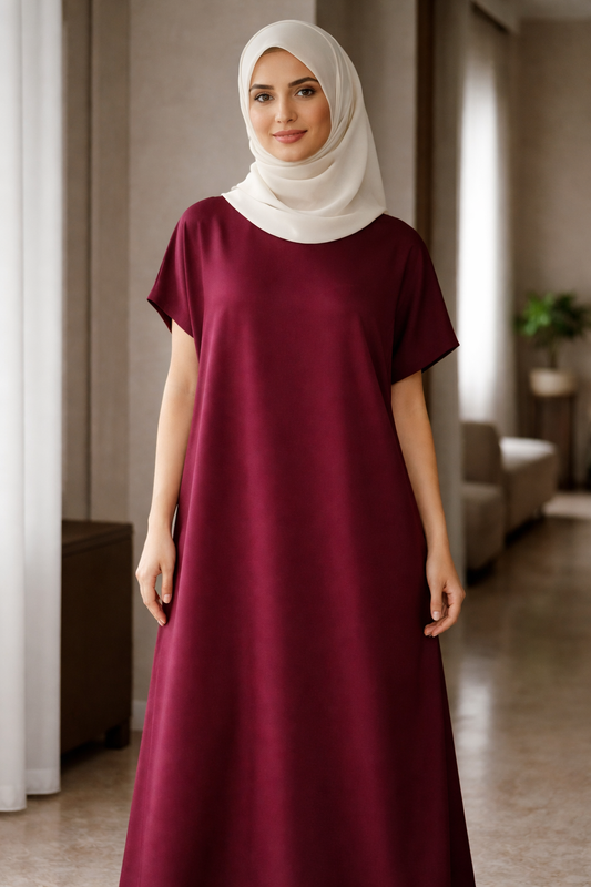 Woman wearing a burgundy under abaya dress and white hijab indoors.|THE LAMORAH
