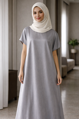 Woman wearing a long gray under abaya dress and white hijab indoors.|THE LAMORAH
