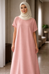 Woman wearing a long pink under abaya dress and beige hijab in an indoor setting |THE LAMORAH
