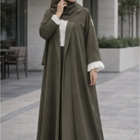 Woman wearing an olive green abaya with white cuffs and collar in an outdoor setting  |THE LAMORAH

