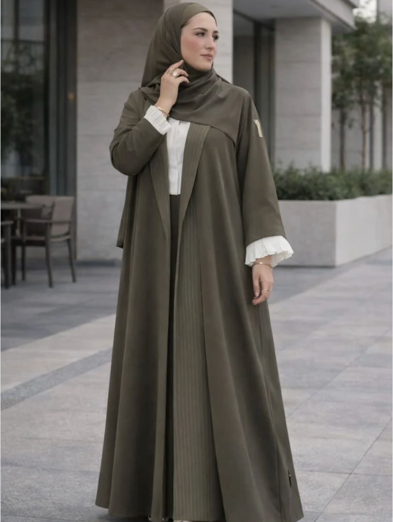 Woman wearing an olive green abaya with white cuffs and collar in an outdoor setting  |THE LAMORAH

