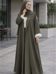 Woman wearing an olive green abaya with white cuffs and collar in an outdoor setting  |THE LAMORAH

