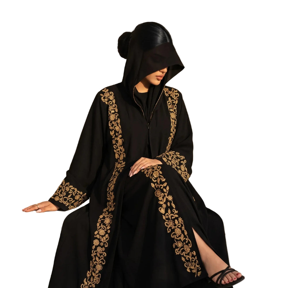 Black hooded abaya with antique gold scrolling embroidery down the front panels and cuffs, worn seated