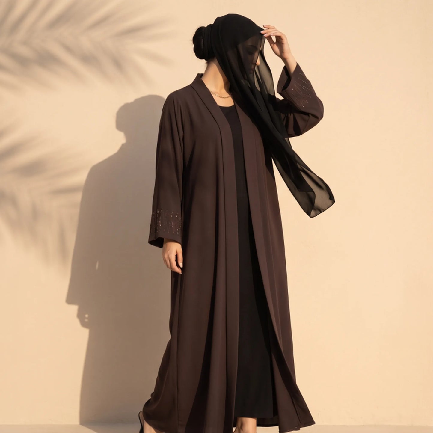 Chocolate brown open-front abaya with a scatter of diamante on the cuffs, worn standing