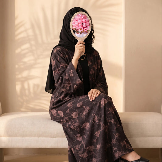Plum abaya with a dusty rose watercolour floral print, worn seated with a black shayla