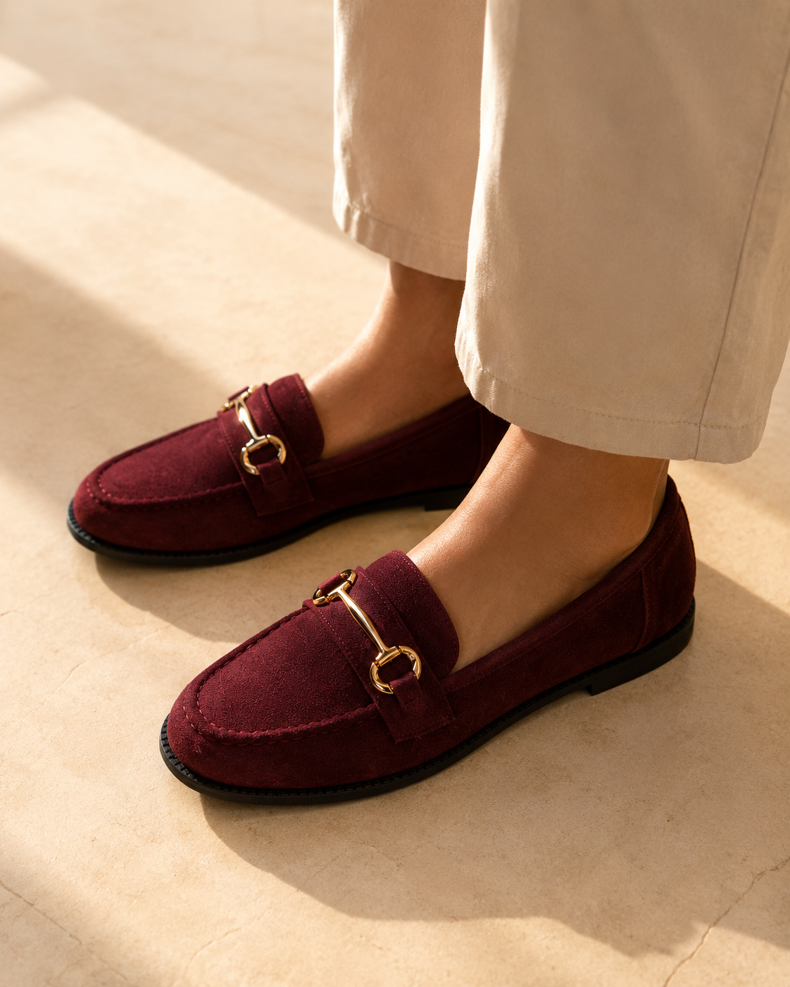 Burgundy suede loafers with gold bar hardware worn with wide stone trousers in the sun, from The Lamorah Dubai