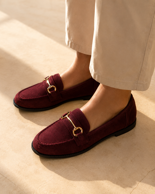 Burgundy suede loafers with gold bar hardware worn with wide stone trousers in the sun, from The Lamorah Dubai