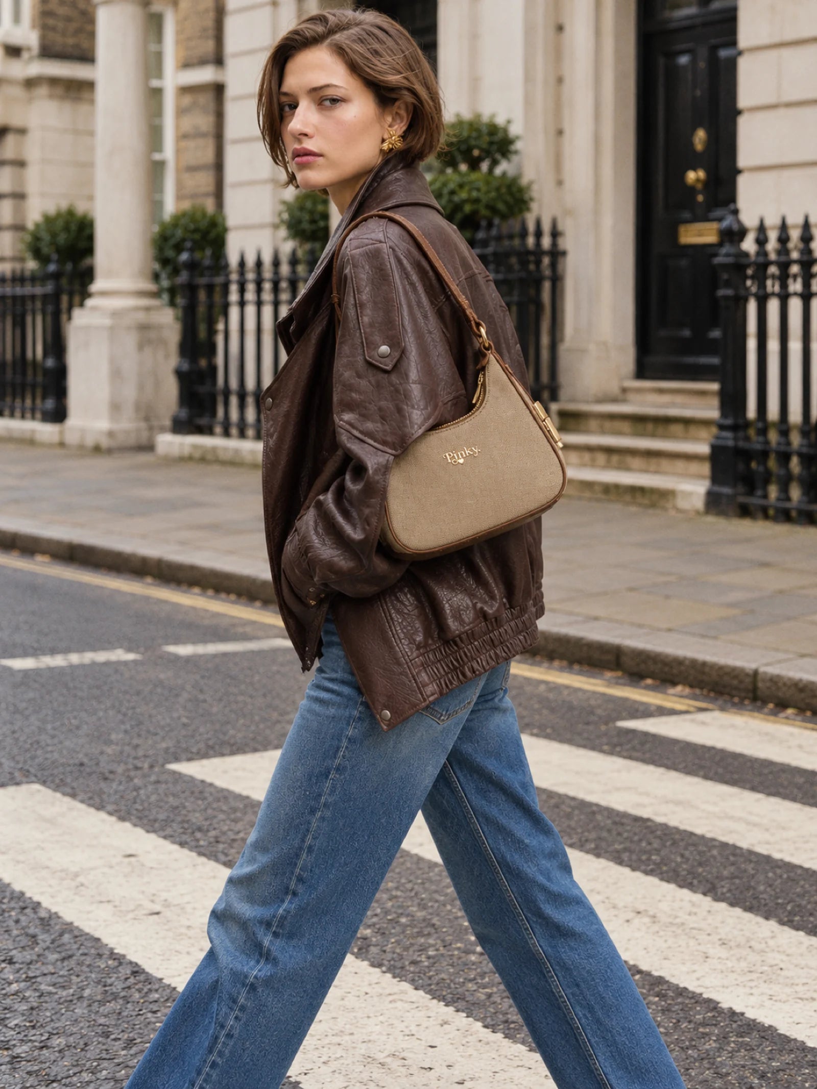 Street-style campaign with a woman carrying a tan shoulder bag at a zebra crossing