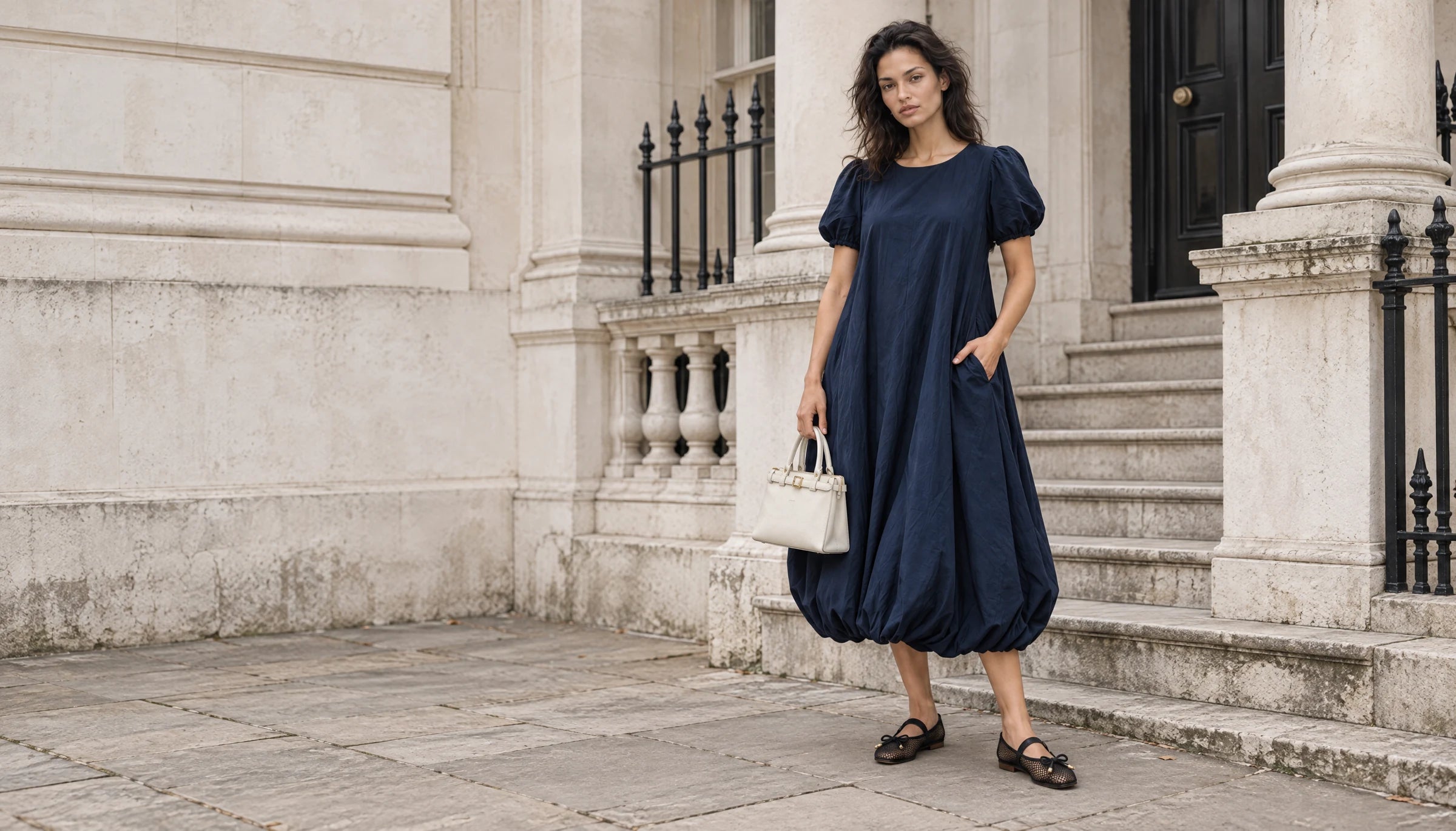 THE LAMORAH navy puff-sleeve dress, ivory top-handle bag and black mesh flats on a London stone staircase